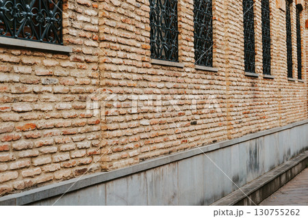 Brick wall with decorative iron bars in a historic urban setting during daylight Brick wall with decorative iron bars in a historic urban setting during daylight 130755262
