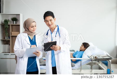 Hospital Ward. Doctor Talks With Professional Head Nurse or Surgeon, They Use Digital tablet Computer. Diverse Team of Health Care Hospital Ward. Doctor Talks With Professional Head Nurse or Surgeon, They Use Digital tablet Computer. Diverse Team of Health Care 130755287