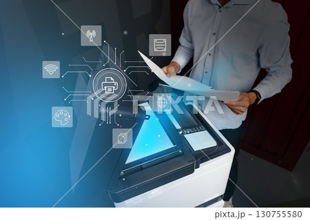 Man operates a multifunction printer in a modern office environment while using technology for document management Man operates a multifunction printer in a modern office environment while using technology for document management 130755580