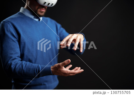 Man engaged in virtual reality simulation wearing headset in indoor space 130755705