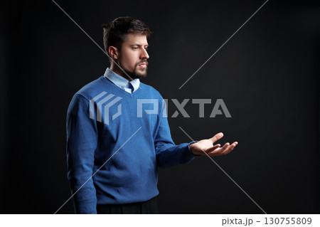 Man in blue sweater gestures thoughtfully in a dark setting conveying introspection and contemplation Man in blue sweater gestures thoughtfully in a dark setting conveying introspection and contemplation 130755809