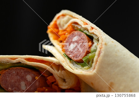 Delicious wrap filled with sausage, fresh vegetables, and vibrant carrots prepared for a satisfying meal Delicious wrap filled with sausage, fresh vegetables, and vibrant carrots prepared for a satisfying meal 130755868