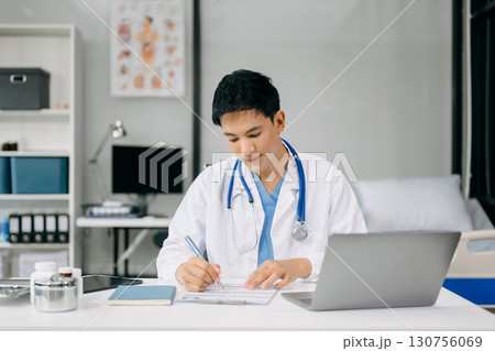 Doctor sit on table in office hospital. Attractive therapist female practitioner pharmacist smile and use tablet and laptop. after success work from treatment 130756069