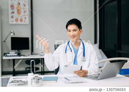 Doctor sit on table in office hospital. Attractive therapist female practitioner pharmacist smile and use tablet and laptop. after success work from treatment 130756083