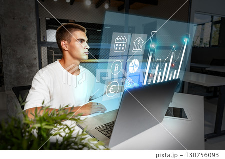 Young man focused on financial analysis using modern technology in an office setting during the day Young man focused on financial analysis using modern technology in an office setting during the day 130756093
