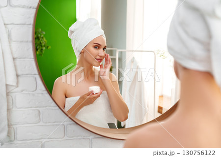 Woman applying skincare in modern bathroom with green accents during morning routine Woman applying skincare in modern bathroom with green accents during morning routine 130756122