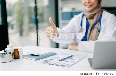 Beautiful physician doctor sit on table in office hospital. Attractive therapist female practitioner pharmacist smile and use tablet and laptop. Beautiful physician doctor sit on table in office hospital. Attractive therapist female practitioner pharmacist smile and use tablet and laptop. 130756255