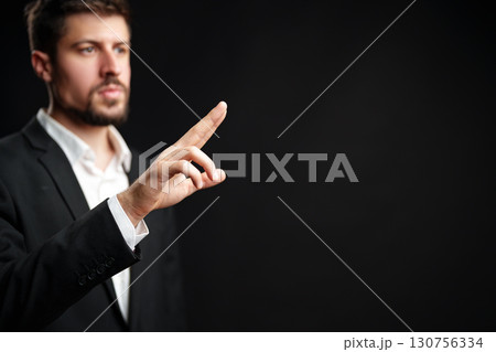 Business professional giving a presentation, emphasizing key points in front of a dark background Business professional giving a presentation, emphasizing key points in front of a dark background 130756334
