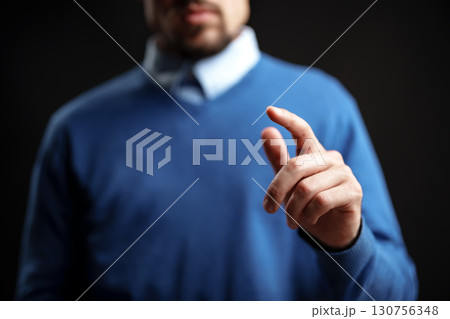 Man in blue sweater gesturing towards the camera in a dark studio environment during an indoor session 130756348