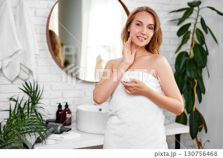 Woman applying skincare in modern bathroom with plants and natural light during morning routine Woman applying skincare in modern bathroom with plants and natural light during morning routine 130756468