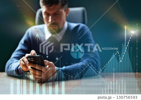Professional man analyzing data on smartphone while seated at a desk in a modern office setting 130756593