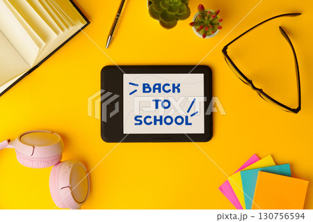Colorful back to school stationery and digital tablet with cheerful message on bright yellow background Colorful back to school stationery and digital tablet with cheerful message on bright yellow background 130756594