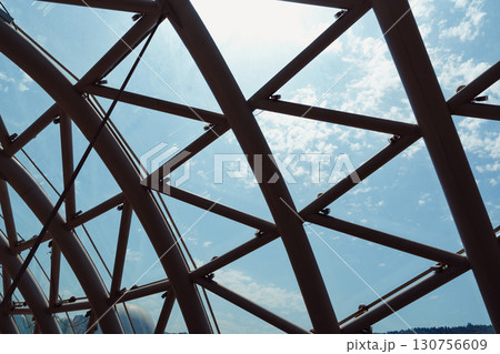 Architectural design features intricate lattice structure against bright blue sky with scattered clouds in afternoon light Architectural design features intricate lattice structure against bright blue sky with scattered clouds in afternoon light 130756609
