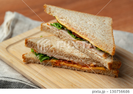 Delicious sandwich with fresh ingredients served on wooden board in cozy setting at lunchtime 130756686