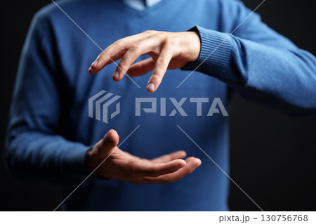 Person demonstrating hand gestures indoors in a dimly lit environment wearing a blue sweater while engaged in a conversation Person demonstrating hand gestures indoors in a dimly lit environment wearing a blue sweater while engaged in a conversation 130756768