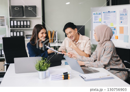 Happy businesspeople while collaborating on a new project in an office. Group of diverse businesspeople using a laptop and tablet Happy businesspeople while collaborating on a new project in an office. Group of diverse businesspeople using a laptop and tablet 130756903