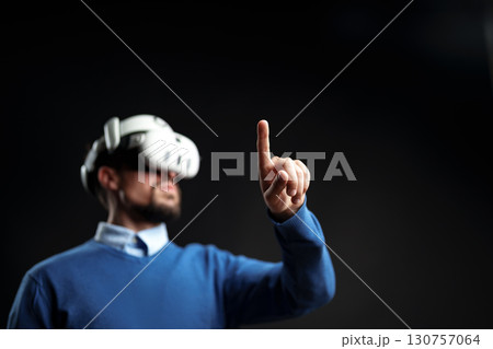 User engages in virtual reality experience while wearing VR headset indoors during a tech demonstration User engages in virtual reality experience while wearing VR headset indoors during a tech demonstration 130757064