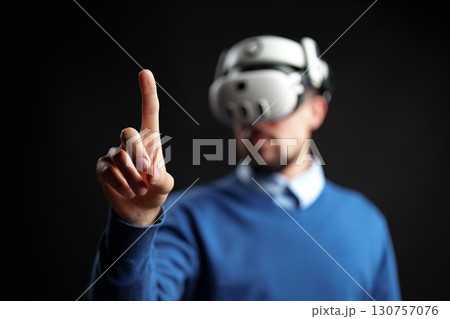 Person engages with virtual reality technology in a dark, immersive environment 130757076