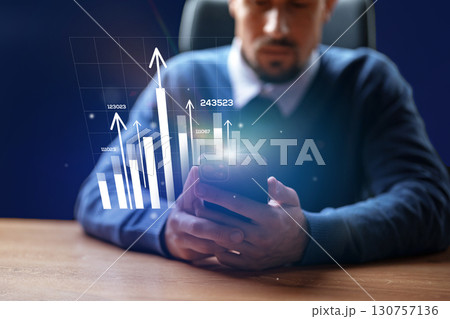 Business professional analyzes growth data on smartphone during office hours in a modern workspace Business professional analyzes growth data on smartphone during office hours in a modern workspace 130757136