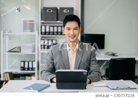 Attractive Asian male office worker business suits smiling at camera in office . teamwork startup concept Attractive Asian male office worker business suits smiling at camera in office . teamwork startup concept 130757216
