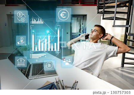 Young man analyzing financial data while talking on the phone in a modern office setting 130757303
