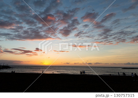 海に沈む夕日と人々のシルエット 130757315