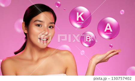 Young woman showcasing benefits of vitamins A, B, and K in a vibrant pink background during a skincare presentation Young woman showcasing benefits of vitamins A, B, and K in a vibrant pink background during a skincare presentation 130757402
