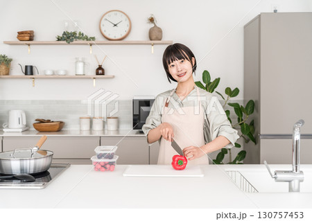 キッチンで料理するエプロン姿の若いアジア人女性 キッチンで料理するエプロン姿の若いアジア人女性 130757453