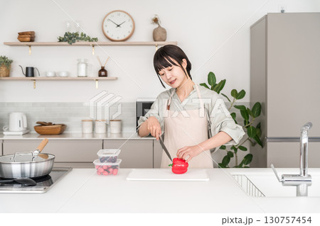 キッチンで料理するエプロン姿の若いアジア人女性 キッチンで料理するエプロン姿の若いアジア人女性 130757454