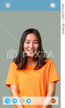 Smiling woman in orange shirt enjoying a virtual call with a friendly expression in simple background Smiling woman in orange shirt enjoying a virtual call with a friendly expression in simple background 130757494