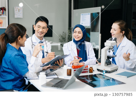 Doctor Talks With Professional Head Nurse or Surgeon, They Use Digital tablet Computer. Diverse Team of Health Care Specialists Discussing Test Result on desk 130757985