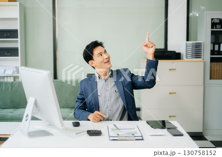 Young attractive Asian male office worker business suits smiling at camera Young attractive Asian male office worker business suits smiling at camera 130758152