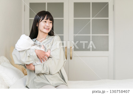 寝室,ベッドルームで赤ちゃんを抱っこする母親(あやす,寝かしつけ,育児) 寝室,ベッドルームで赤ちゃんを抱っこする母親(あやす,寝かしつけ,育児) 130758407