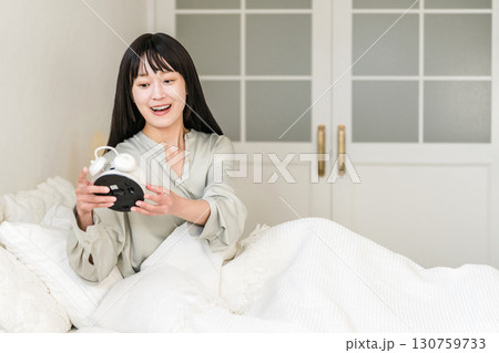 目覚まし時計を見て驚くびっくりする若いアジア人女性(寝坊,遅刻,寝過ごす) 目覚まし時計を見て驚くびっくりする若いアジア人女性(寝坊,遅刻,寝過ごす) 130759733