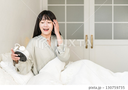 目覚まし時計を見て驚くびっくりする若いアジア人女性(寝坊,遅刻,寝過ごす) 目覚まし時計を見て驚くびっくりする若いアジア人女性(寝坊,遅刻,寝過ごす) 130759735