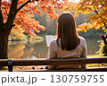 紅葉した公園で本を読む女性 130759755