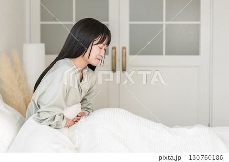 ベッドルームで腹痛・生理痛に悩む日本人女性 130760186