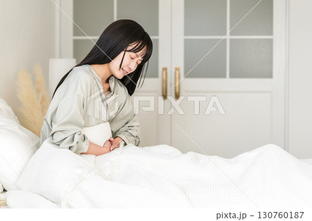 ベッドルームで腹痛・生理痛に悩む日本人女性 130760187