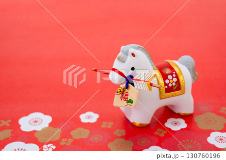 午年　年賀素材　破魔矢を咥えた白午と梅の花びら　赤色バック 130760196