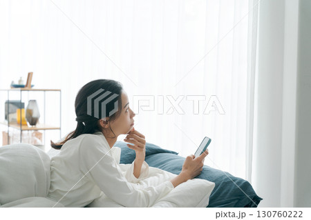 朝寝坊をしてスマホを持つ女性 130760222