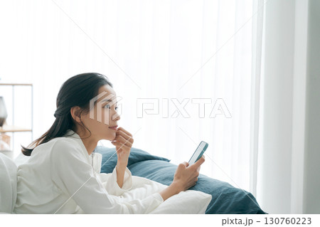朝寝坊をしてスマホを持つ女性 130760223