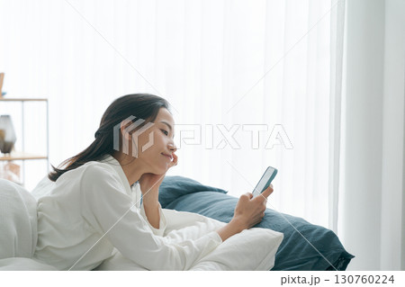 朝寝坊をしてスマホを持つ女性 130760224
