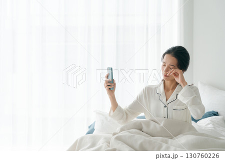 朝寝坊をしてスマホを持つ女性 朝寝坊をしてスマホを持つ女性 130760226