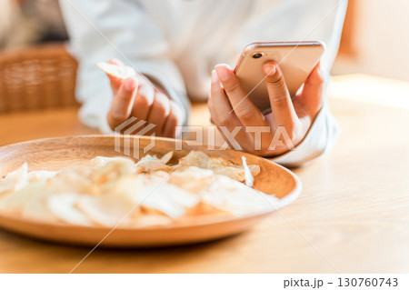 スマホを見ながらポテトチップ,スナック菓子,おやつを食べる子供 130760743