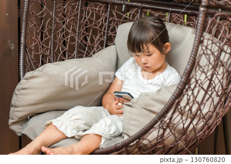 ハンギングチェアに座りスマホを見ている少女 130760820