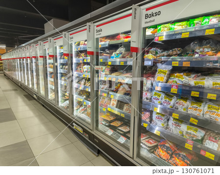 A wide-angle shot of a supermarket aisle with refrigerated display cases containing a variety of frozen and processed meat products like sausage and meatballs. A wide-angle shot of a supermarket aisle with refrigerated display cases containing a variety of frozen and processed meat products like sausage and meatballs. 130761071