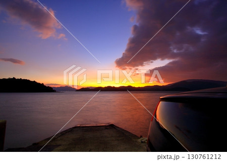 夕暮れ時に車を停めて海を眺める 130761212