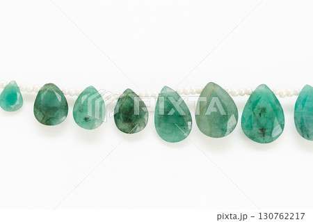 白背景に映えるエメラルドのブリオレットビーズストランドとタッセル 130762217