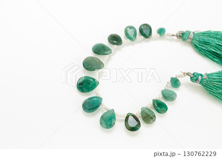 白背景に映えるエメラルドのブリオレットビーズストランドとタッセル 130762229