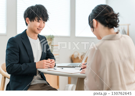 商談テーブルで女性顧客と打ち合わせ,カウンセリング,ヒアリングをする若いアジア人ビジネスマン 130762645
